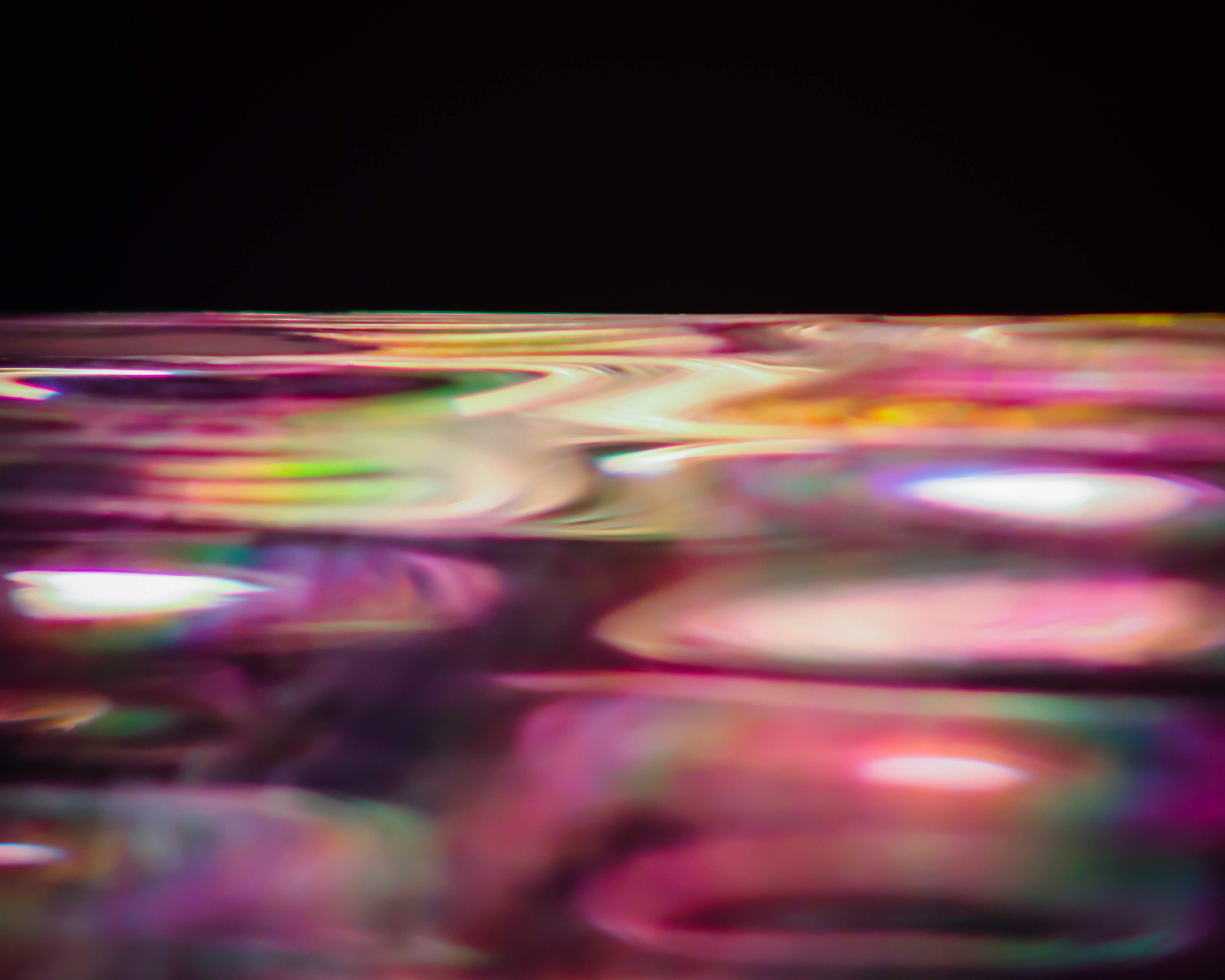 A photograph of a glass vase on a black background, made to look like a colorful ocean